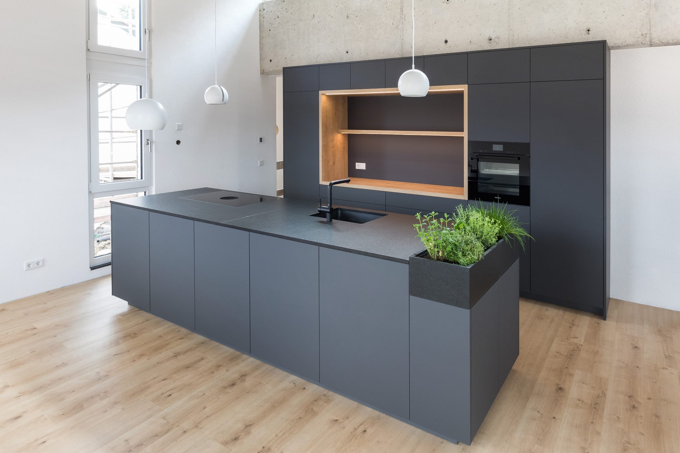 Schwarzgraue Küche mit Pflanzenelement