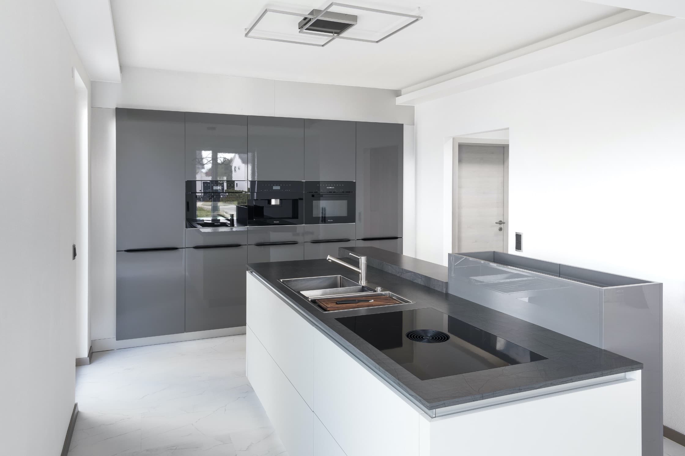 Grau-weiße Küche mit Kochinsel und ausziehbarer Arbeitsplatte