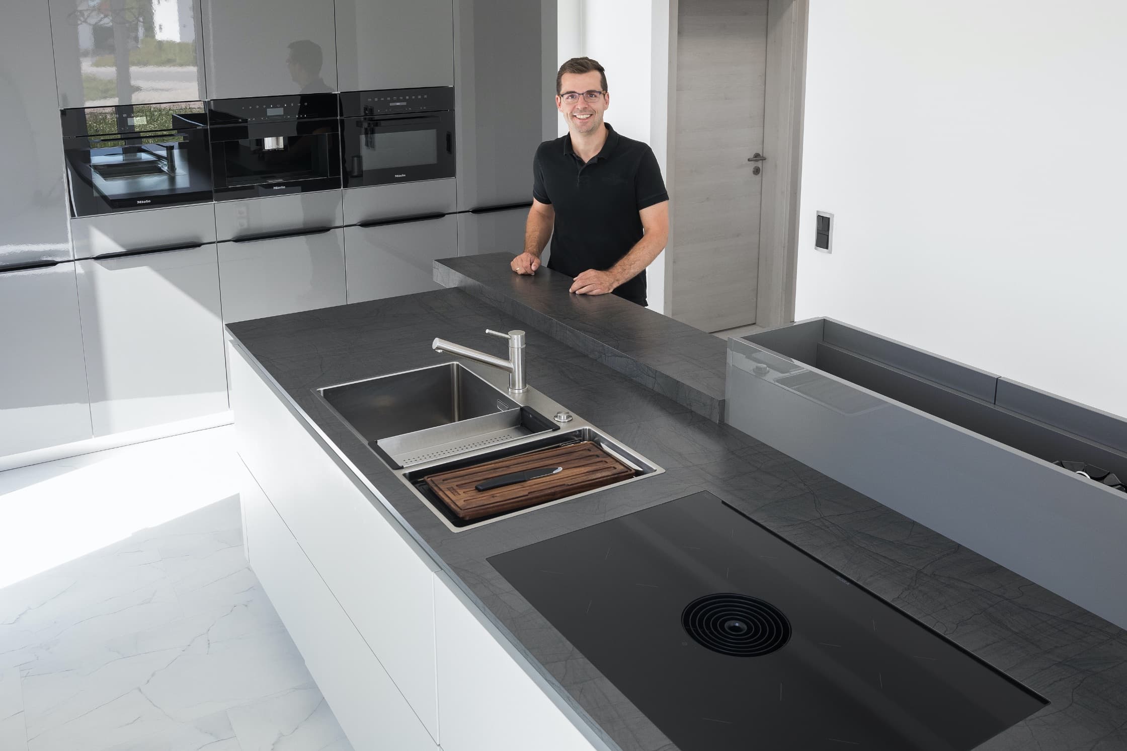 Grau-weiße Küche mit Kochinsel und ausziehbarer Arbeitsplatte