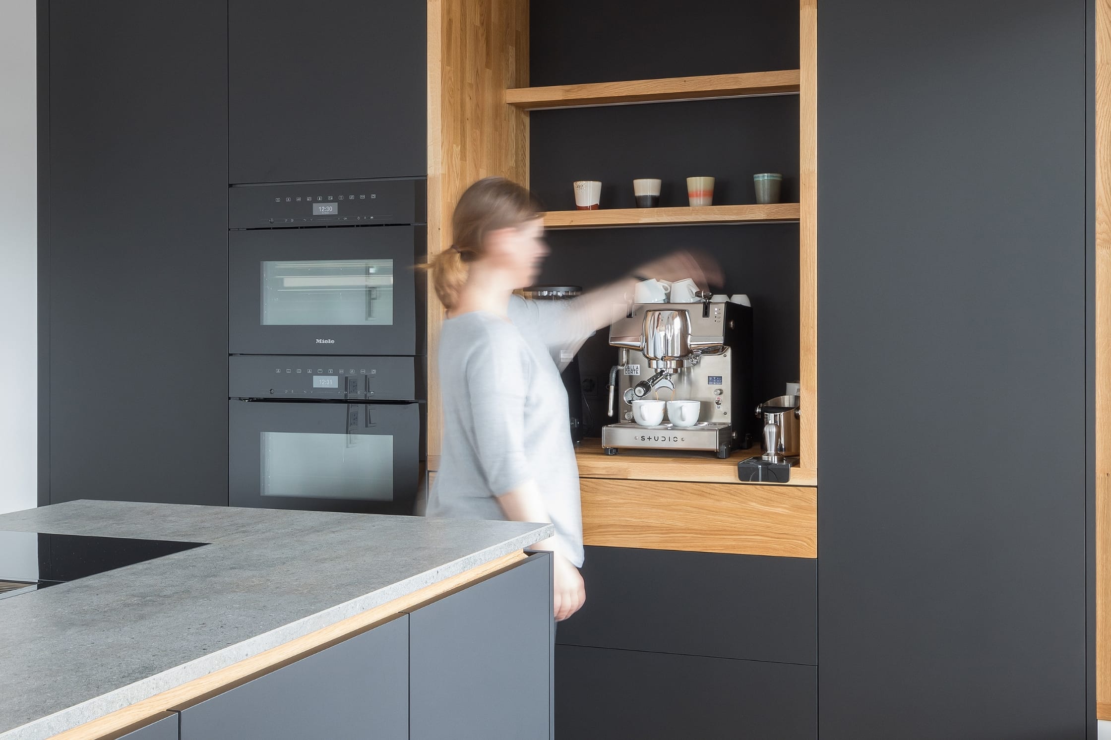 Schwarze Küche mit Holzveredelungen und Nische für eine Kaffeebar